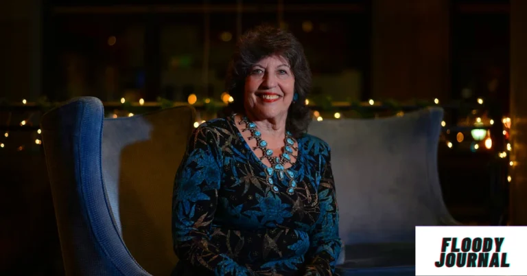 Carol Schwartz sitting on a blue chair in a patterned blue and black dress with a turquoise necklace, with warm string lights in the background. Meta description: Carol Schwartz biography—discover her age, height, net worth, family, and career highlights in 2025.