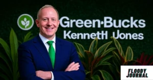 MyGreenBucks Kenneth Jones founder in blue suit with green tie standing confidently in front of company logo and plants